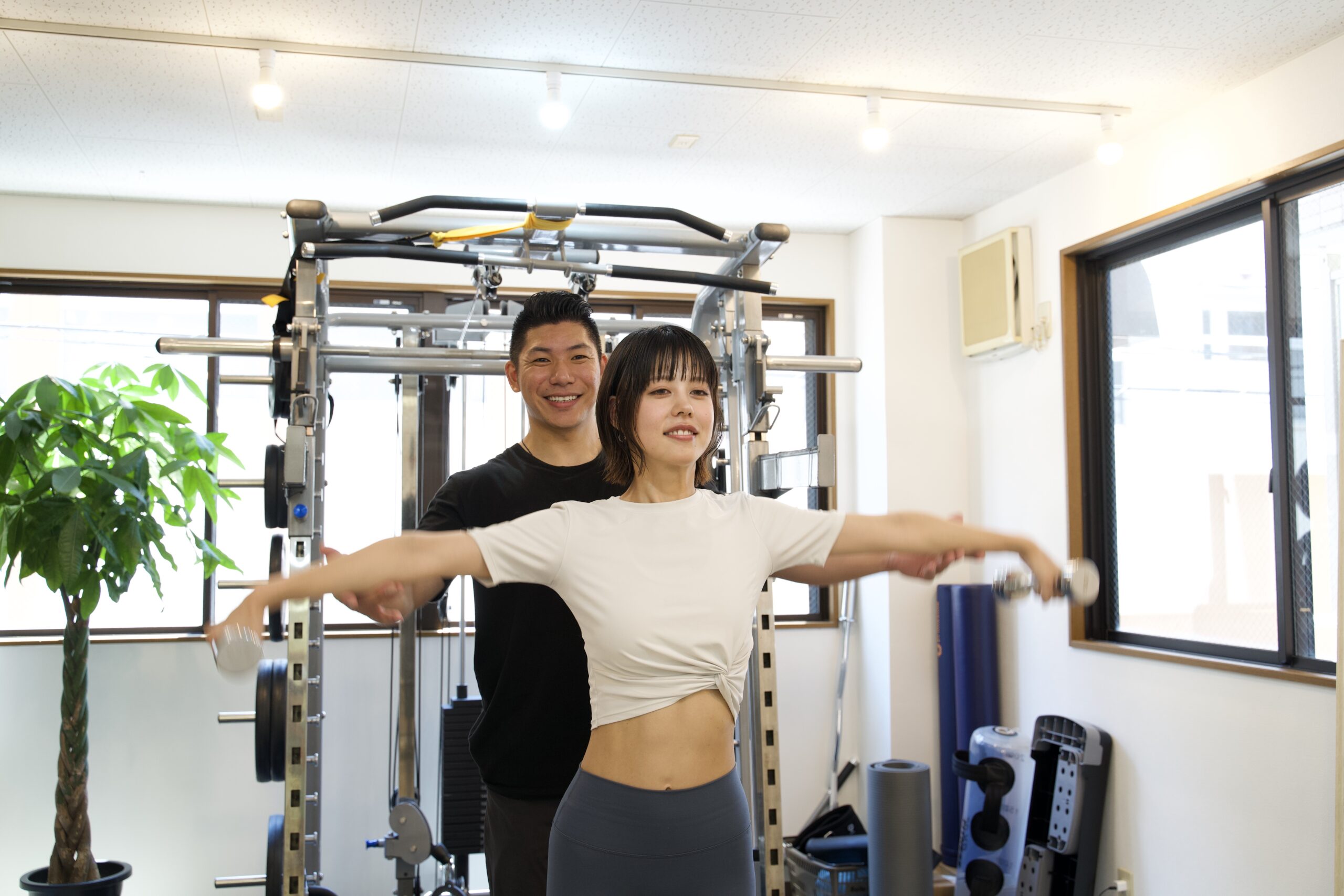 明るい完全個室で笑顔でトレーニングする女性会員
