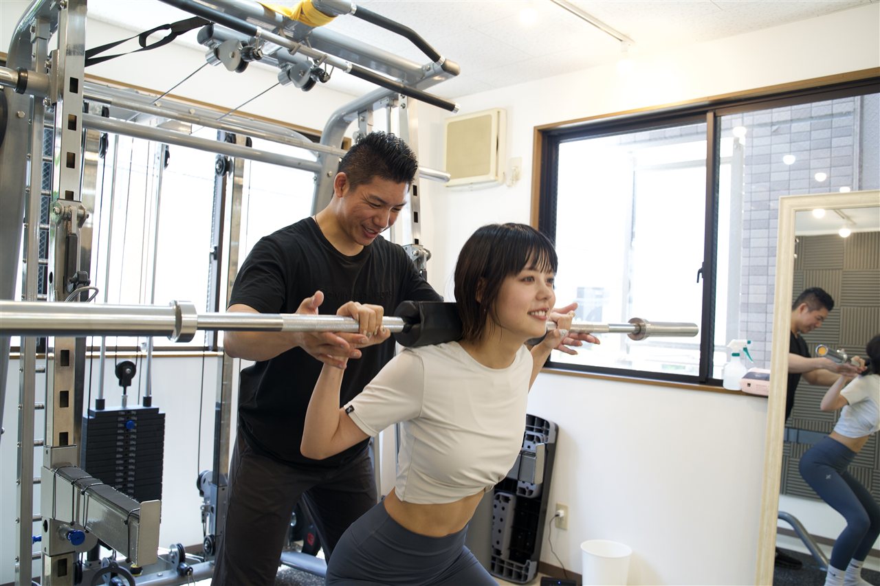 パーソナルトレーナーが正しいフォーム・姿勢を指導する様子