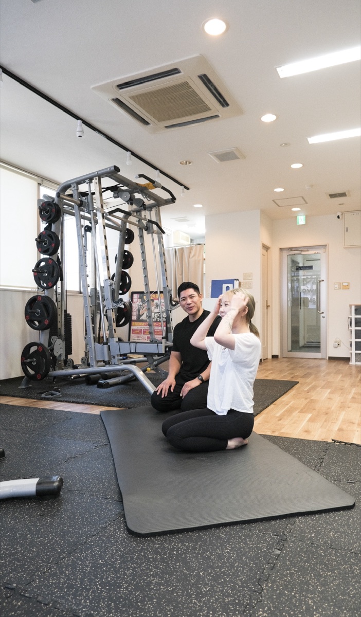 トレーナーが肩まわりのストレッチをサポートしている様子
