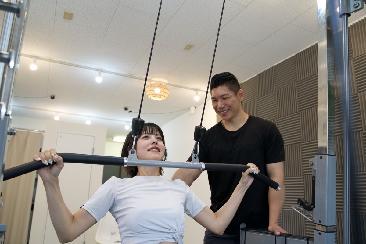 パーソナルトレーニングでマシンの使い方を指導するトレーナー
