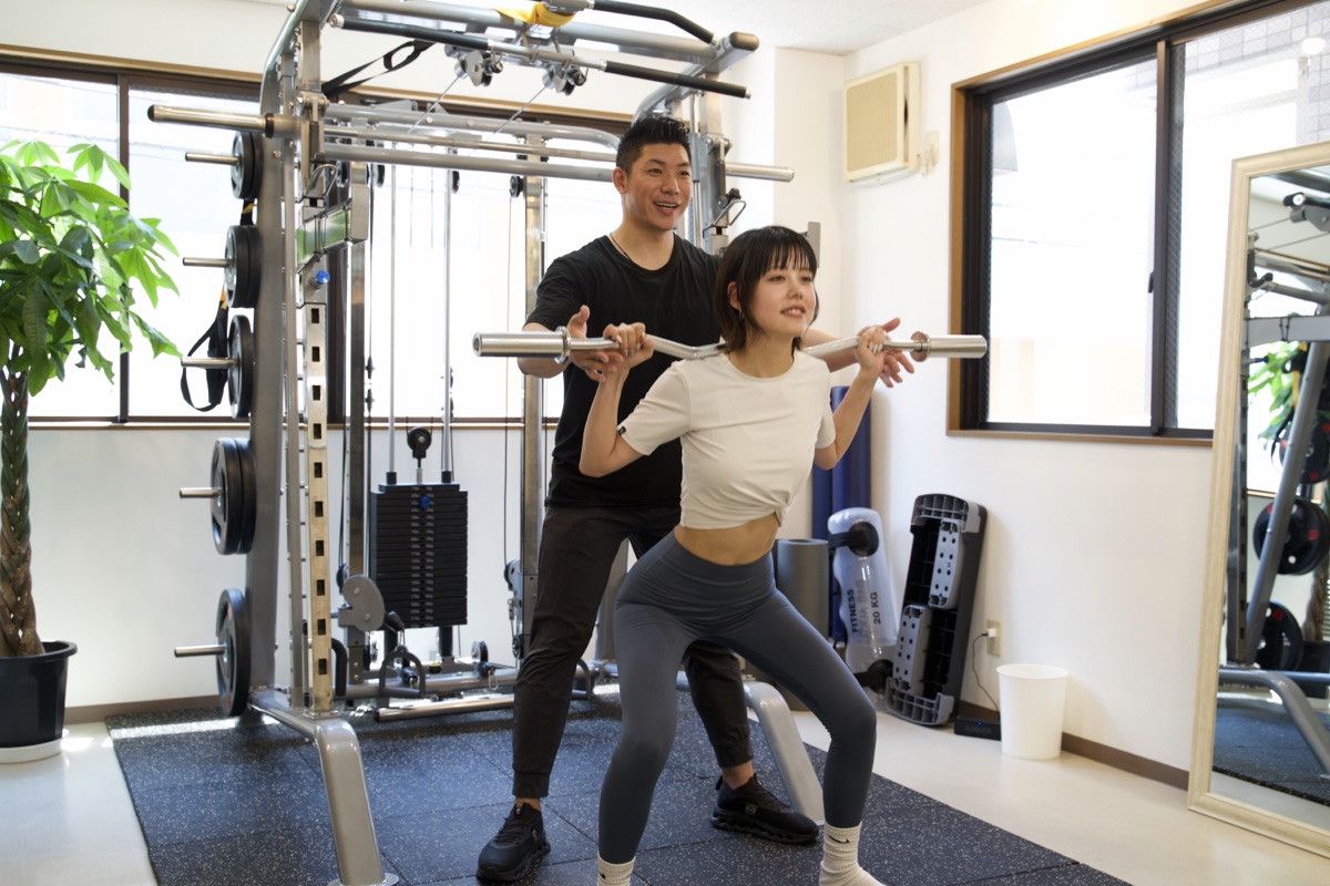 パーソナルジムで背中と肩甲骨まわりを意識したトレーニングを行う女性とトレーナー