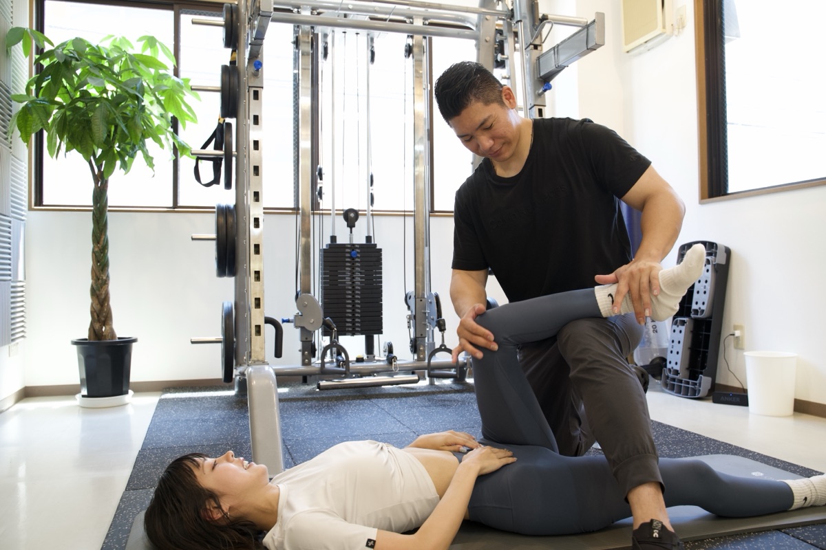 股関節のストレッチをトレーナーが補助しているところ