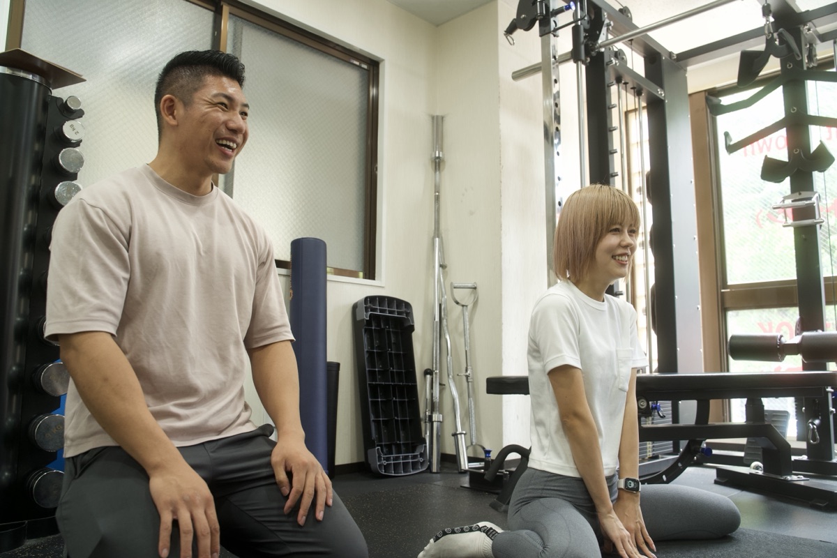 トレーニング後に笑顔で話すトレーナーと女性