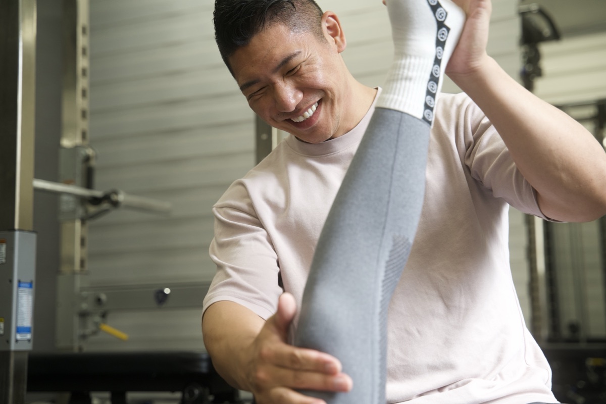 トレーナーが脚を持ち上げてストレッチをサポートする様子