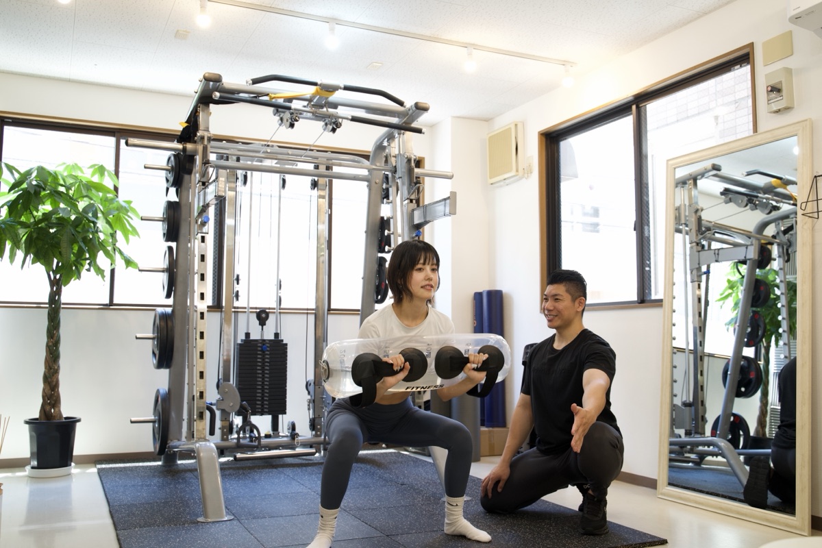 自宅でもできるスクワットをトレーナーが指導している様子