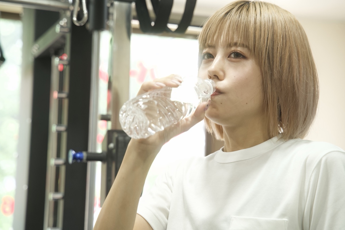 パーソナルトレーニングの合間に水を飲む女性