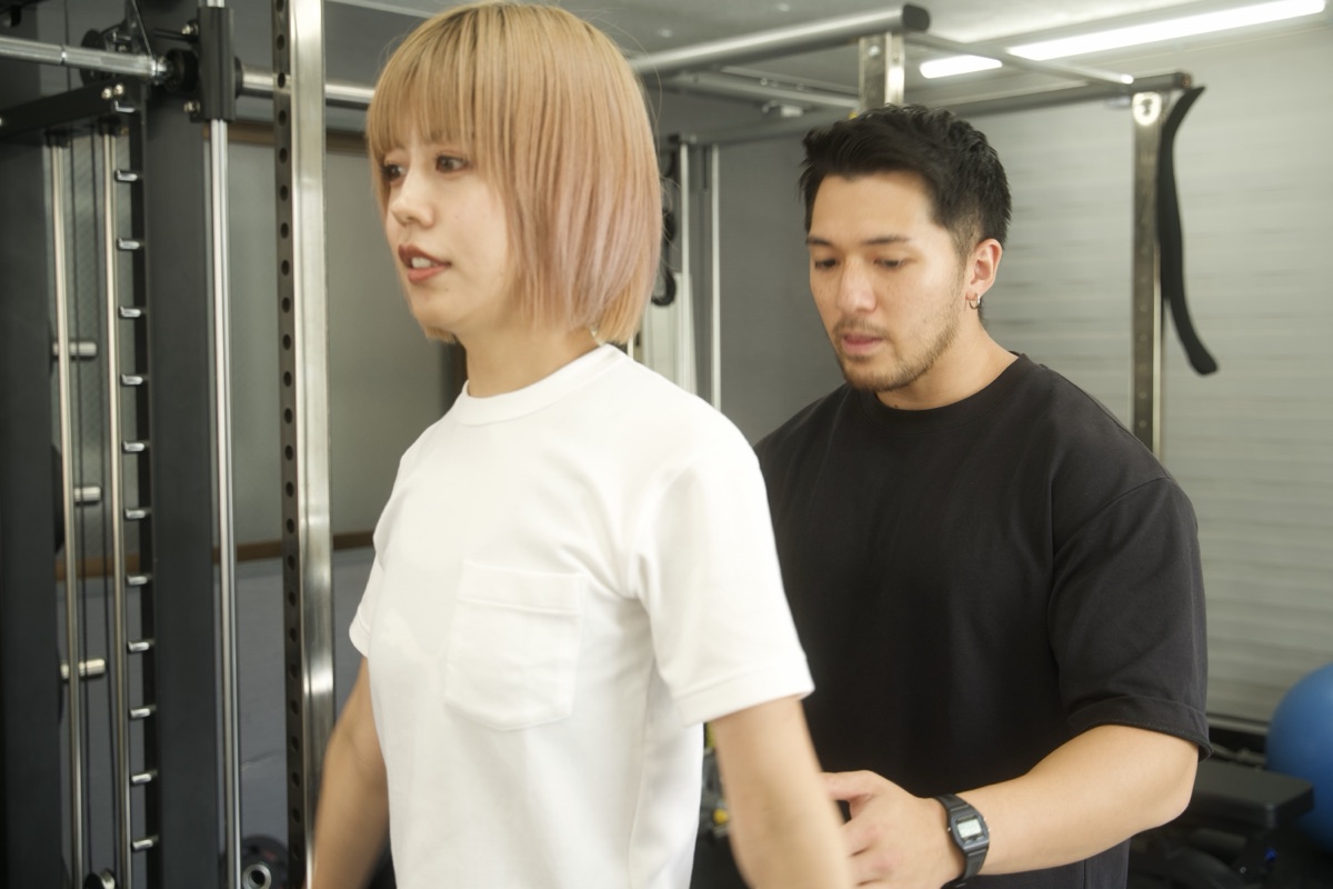 パーソナルトレーナーが立ち姿勢と体の使い方を確認する様子
