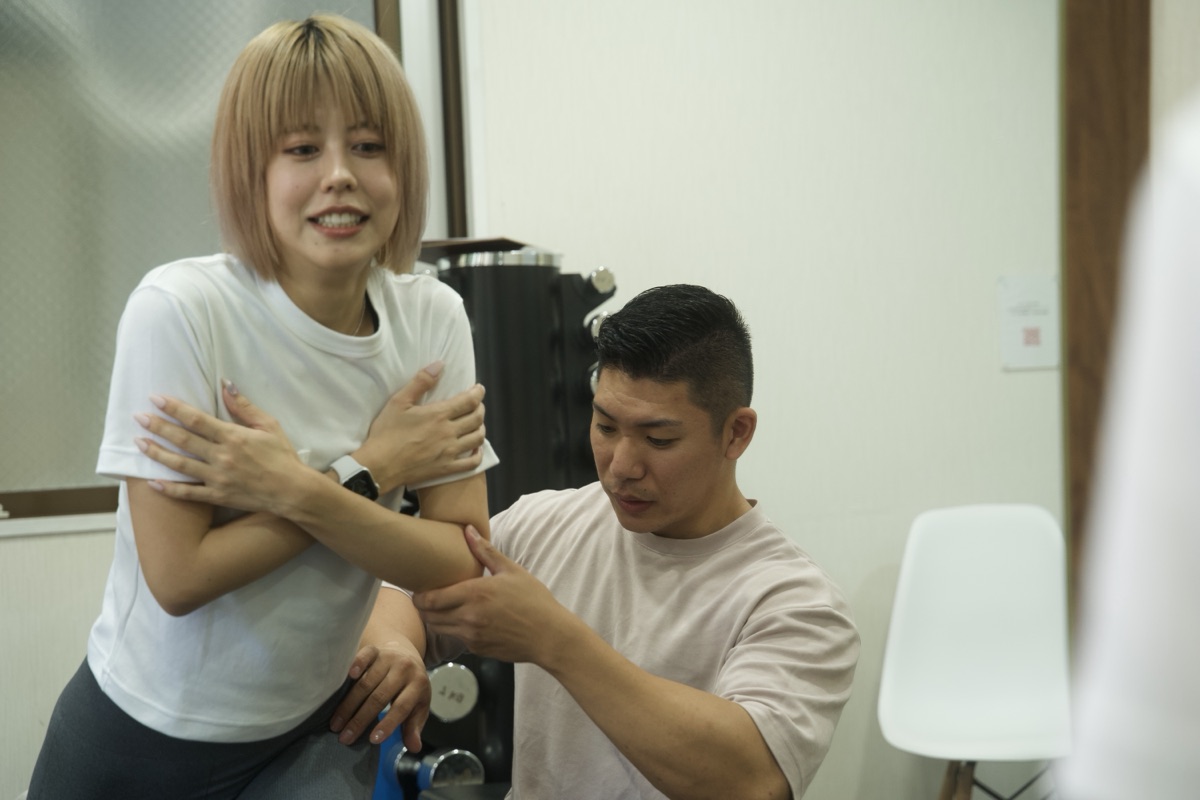 灘のパーソナルジムでトレーナーと一緒にストレッチをする女性
